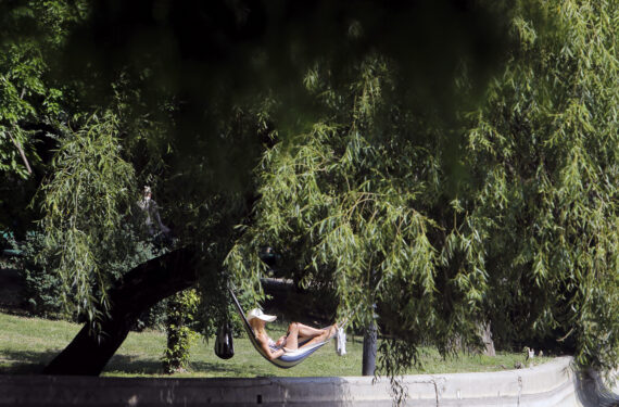 BUCHAREST, Seorang wanita beristirahat di hammock di tempat teduh saat gelombang panas melanda di sebuah taman di pusat kota Bucharest, Rumania, pada 21 Juni 2022. (Xinhua/Cristian Cristel)