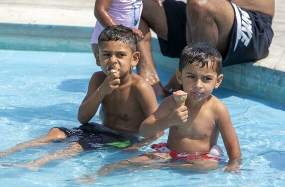 ATHENA, Anak-anak menikmati es krim sembari berendam di air mancur di tengah gelombang panas di Athena, Yunani, pada 22 Juni 2022. (Xinhua/Marios Lolos)