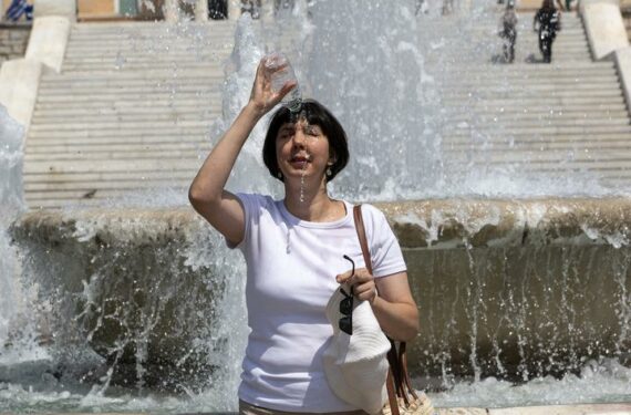 ATHENA, Seorang wanita menuangkan air ke atas kepalanya di tengah gelombang panas di Athena, Yunani, pada 22 Juni 2022. (Xinhua/Marios Lolos)