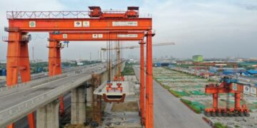 JAKARTA, Foto dari udara yang diabadikan pada 24 Juni 2022 ini menunjukkan proses pengangkatan box girder terakhir Casting Yard No.1 Kereta Cepat Jakarta-Bandung (KCJB) di Bekasi, Provinsi Jawa Barat. Casting Yard No.1 KCJB pada Senin (27/6) merampungkan pemasangan 1.018 box girder, meletakkan fondasi yang solid bagi penyelesaian proyek jalur kereta itu pada Juni 2023. (Xinhua/Tao Yuanyu)