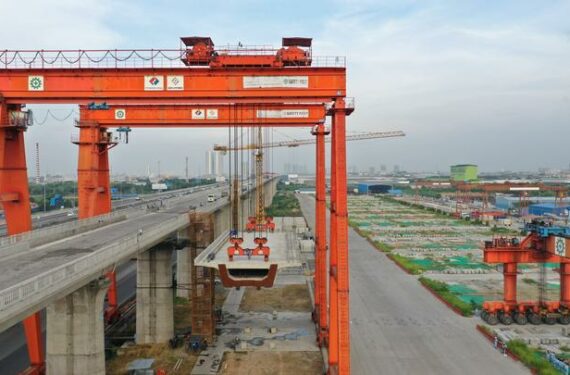 JAKARTA, Foto dari udara yang diabadikan pada 24 Juni 2022 ini menunjukkan proses pengangkatan box girder terakhir Casting Yard No.1 Kereta Cepat Jakarta-Bandung (KCJB) di Bekasi, Provinsi Jawa Barat. Casting Yard No.1 KCJB pada Senin (27/6) merampungkan pemasangan 1.018 box girder, meletakkan fondasi yang solid bagi penyelesaian proyek jalur kereta itu pada Juni 2023. (Xinhua/Tao Yuanyu)