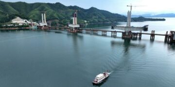 HEFEI, Foto dari udara yang diabadikan pada 29 Juni 2022 ini menunjukkan menara utama jembatan besar Danau Taiping di Huangshan, Provinsi Anhui, China timur. Struktur penutup (cap) menara utama ketiga di jembatan besar Danau Taiping telah dipasang pada Rabu (29/6), menandai rampungnya pembangunan tiga menara utama di jembatan itu. Jembatan besar Danau Taiping merupakan proyek krusial di Jalur Kereta Chizhou-Huangshan dengan total panjang mencapai 926,1 meter. (Xinhua/Weng Xiaohu)
