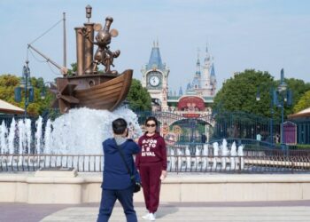 Seorang wisatawan berpose untuk difoto di pintu masuk Shanghai Disneyland di Shanghai, China timur, pada 3 November 2021. (Xinhua/Ding Ting)