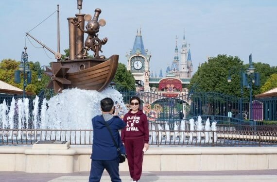 Seorang wisatawan berpose untuk difoto di pintu masuk Shanghai Disneyland di Shanghai, China timur, pada 3 November 2021. (Xinhua/Ding Ting)