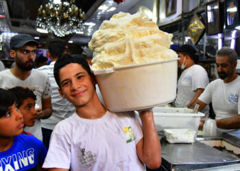 DAMASKUS, Seorang anak laki-laki membawa satu tong es krim Arab di sebuah toko di Damaskus, Suriah, pada 8 Agustus 2022. (Xinhua/Ammar Safarjalani)
