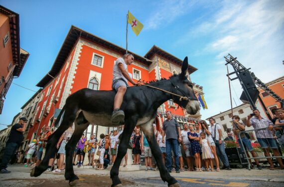 VODNJAN, Seorang pria mengikuti perlombaan balap keledai di Vodnjan, Kroasia, pada 13 Agustus 2022. (Xinhua/PIXSEL/Srecko Niketic)