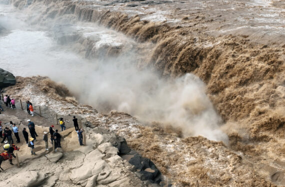 YAN'AN, Foto dari udara yang diabadikan pada 15 September 2022 ini menunjukkan sejumlah wisatawan sedang menikmati pemandangan Air Terjun Hukou di Sungai Kuning di Provinsi Shaanxi, China barat laut. Air terjun Hukou belakangan ini mengalami peningkatan debit air. (Xinhua/Tao Ming)
