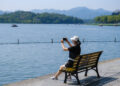 HANGZHOU, Seorang wisatawan mengabadikan foto kawasan wisata Danau Barat saat libur Hari Nasional China di Hangzhou, Provinsi Zhejiang, China timur, pada 2 Oktober 2022. (Xinhua/Xu Yu)