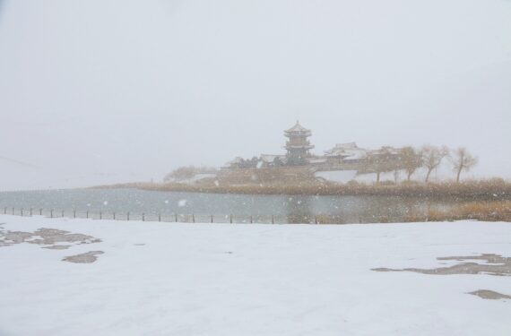 DUNHUANG, Foto yang diabadikan pada 27 November 2022 ini memperlihatkan pemandangan salju objek wisata Gunung Mingsha dan Mata Air Bulan Sabit di Kota Dunhuang, Provinsi Gansu, China barat laut. (Xinhua/Zhang Xiaoliang)