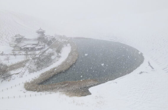 DUNHUANG, Foto dari udara yang diabadikan pada 27 November 2022 ini memperlihatkan pemandangan salju objek wisata Gunung Mingsha dan Mata Air Bulan Sabit di Kota Dunhuang, Provinsi Gansu, China barat laut. (Xinhua/Zhang Xiaoliang)