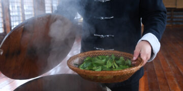 CHANGXING, Lin Ruiyang, seorang pewaris teknik pembuatan teh Zisun, mengukus daun teh segar di wilayah Changxing, Provinsi Zhejiang, China timur, pada 30 November 2022. Teh Zisun, yang diproduksi di wilayah tersebut, memiliki sejarah lebih dari 1.000 tahun. Teh Zisun disebut sebagai teh persembahan pada era Dinasti Tang (618-907). (Xinhua/Xu Yu)