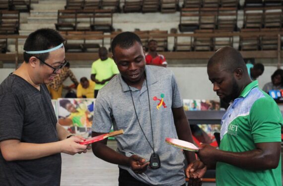 COTONOU, Para pemain berkomunikasi dengan wasit (tengah) sebelum pertandingan tenis meja sebagai bagian dari perayaan 50 tahun persahabatan antara China dan Benin di Cotonou, Benin, pada 4 Desember 2022. (Xinhua/Seraphin Zounyekpe)